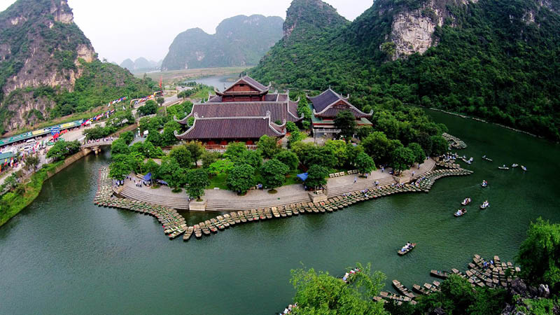 Gröna berg och kanal med små båtar vid hotell Hidden Charm i staden Ninh Binh, Vietnam.